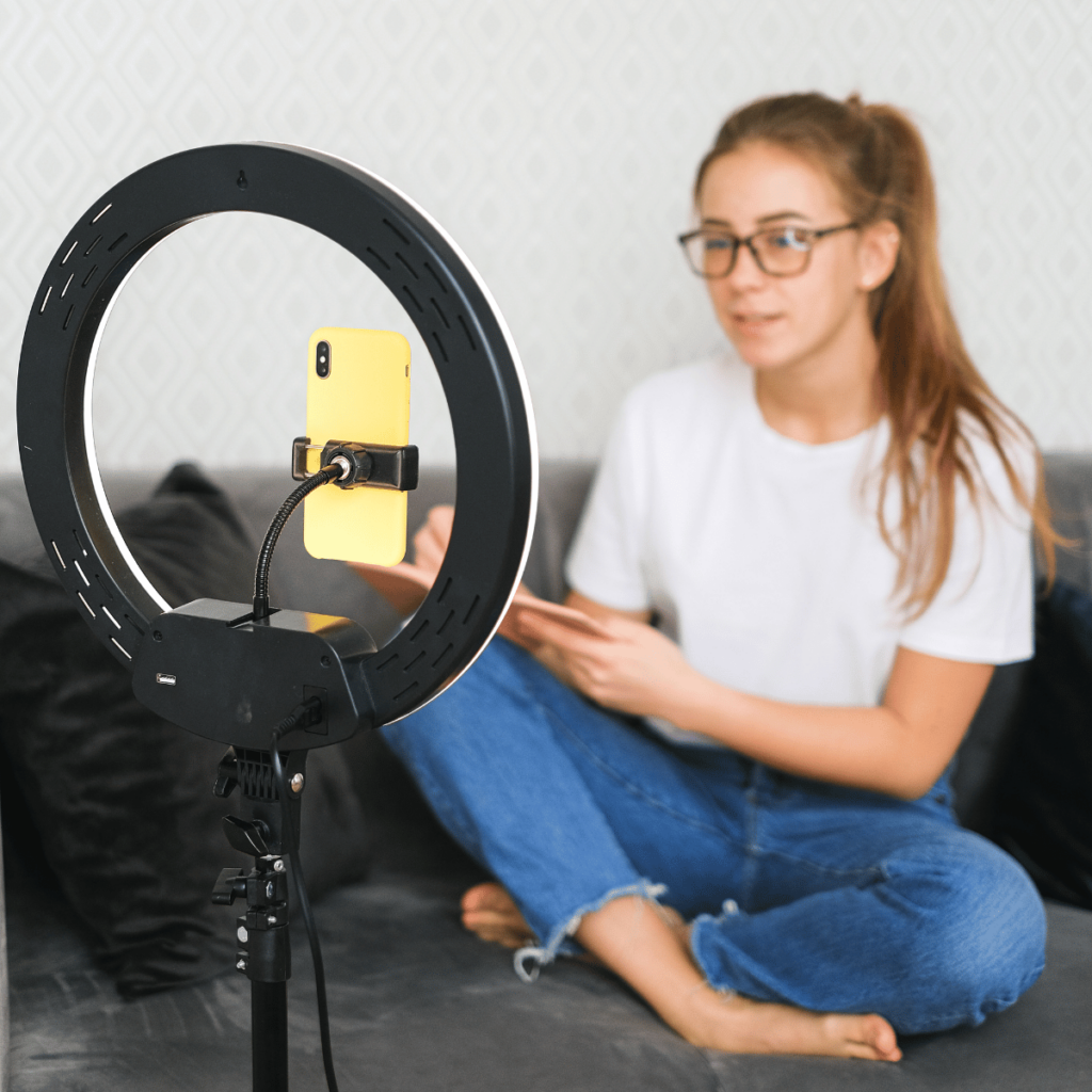 Finfluencers: A woman talks into a camera phone, lit by a ring light.