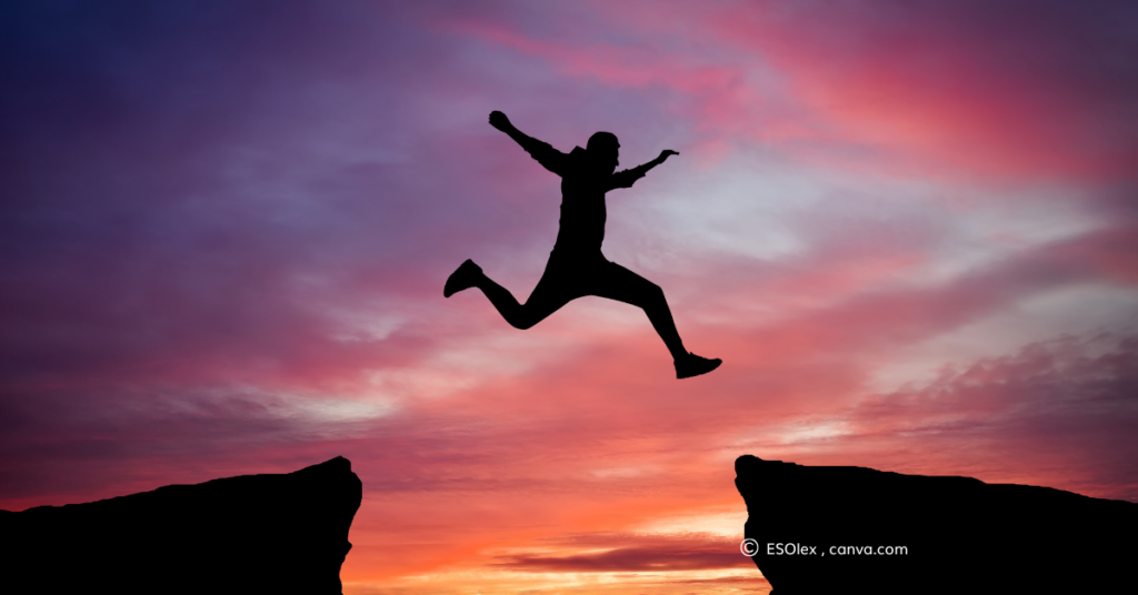 A person jumping the gap between two cliffs at sunset. By ESOlex, canva.com