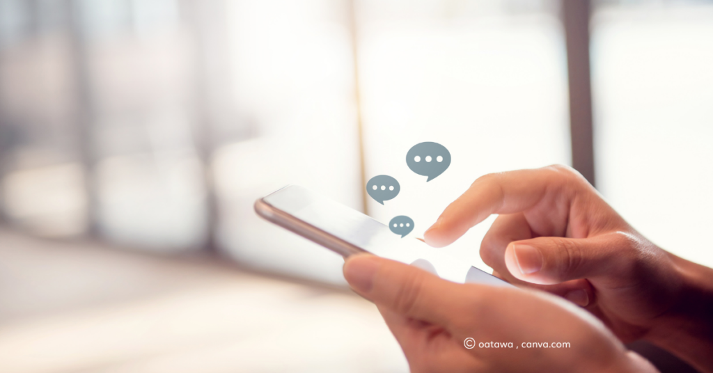 A picture of a hand holding a phone, with small graphic speech bubbles coming out of it. By oatawa, canva.com