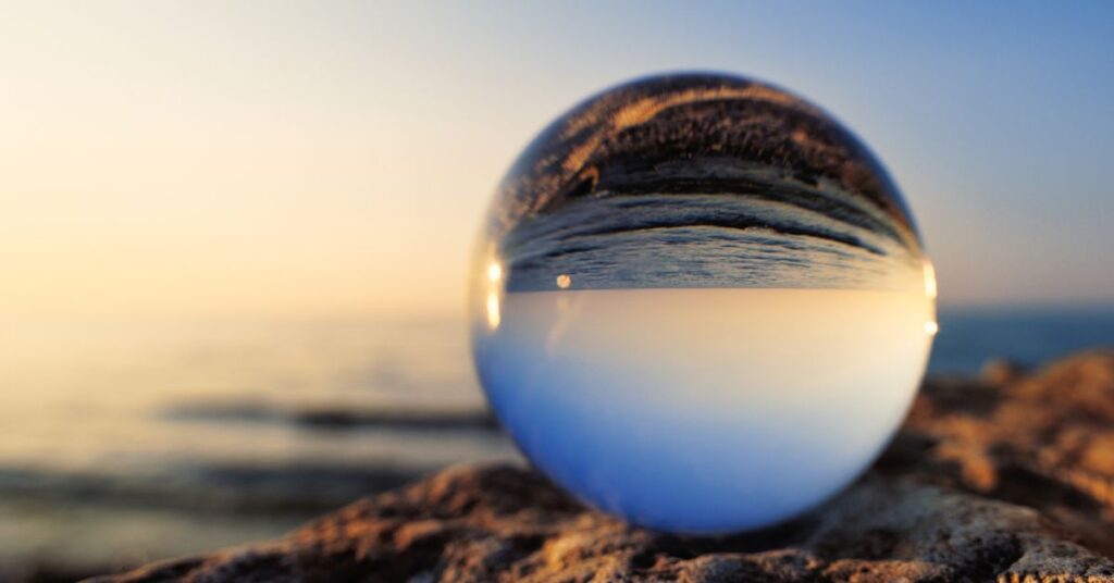 Reflecting on 2023: A glass ball reflects the ocean behind it.