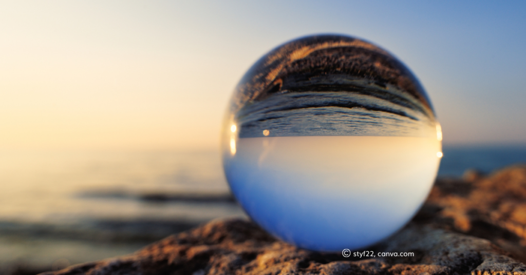 A glass orb reflecting the seafront. By styf22, canva.com