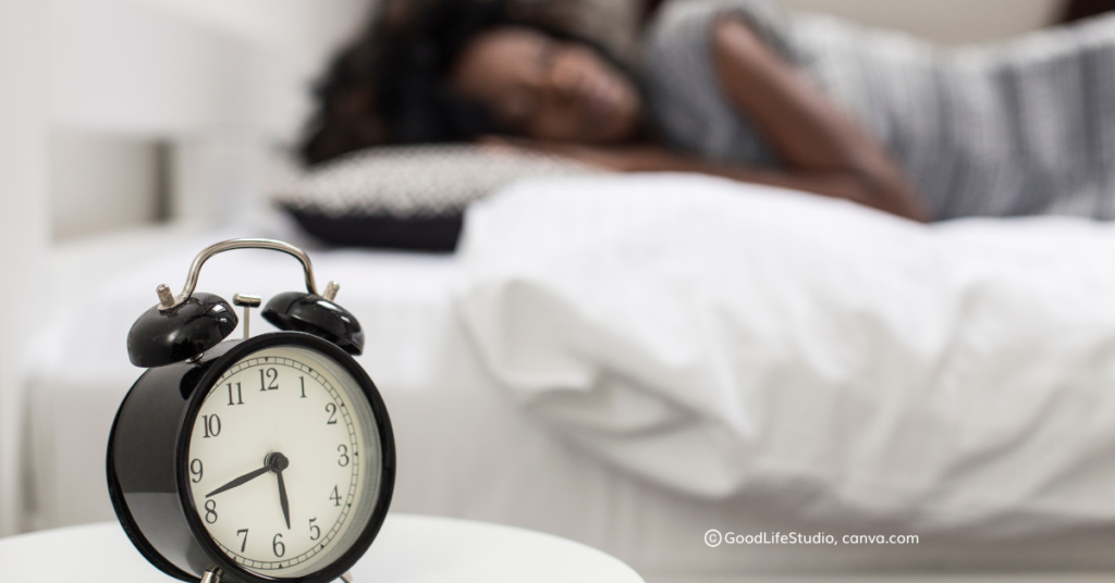 A picture of a woman sleeping with an alarm clock in the foreground. c_GoodLifeStudio